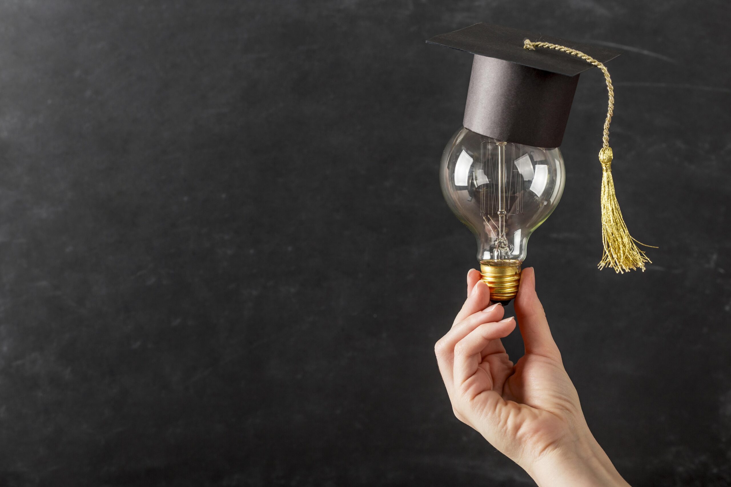 person-holding-light-bulb-with-graduation-cap person holding light bulb with graduation cap scaled